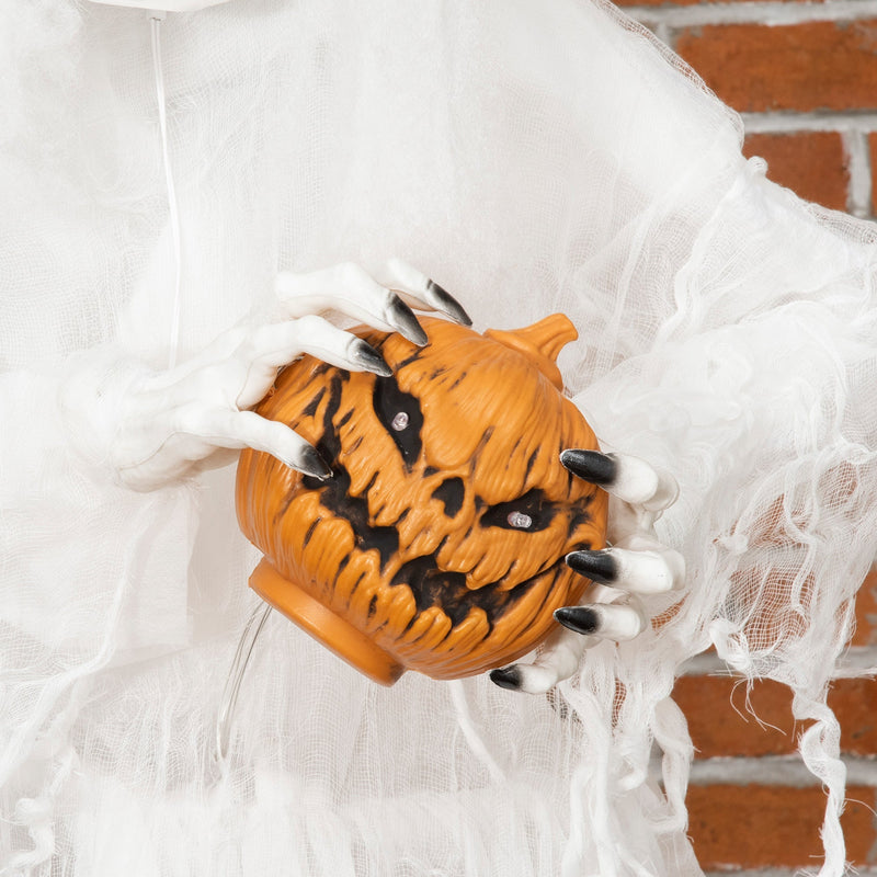 Close-up of the witch's hands holding the blue-lit carved pumpkin