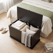 Overhead view of the black storage bench packed with folded bedding, cushions and a knitted throw