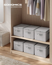 Six dove grey storage boxes with zipped lids arranged on a wardrobe shelf next to hanging clothes