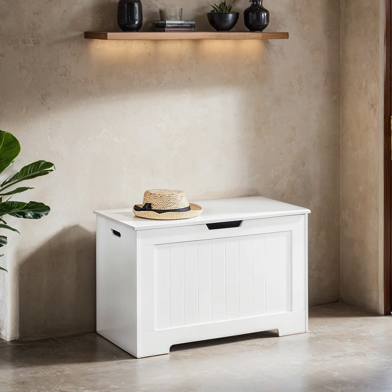 White storage chest bench against a plaster wall with a straw hat on the closed lid