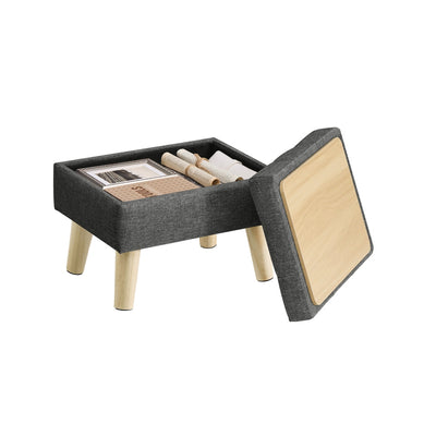 Slate grey linen-look storage ottoman with wooden legs shown with its hinged lid lifted open to reveal books stored inside the hollow compartment.