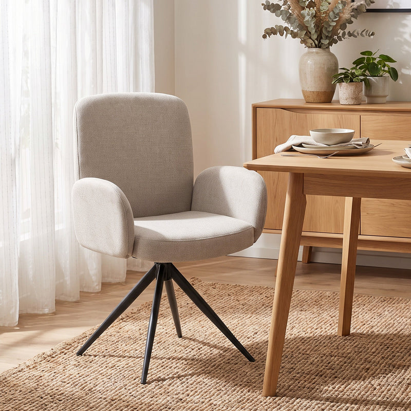 Light brown swivel accent chair pulled up to a wooden dining table