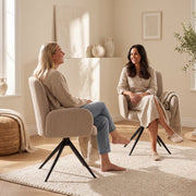 Two women chatting face to face in light brown swivel accent chairs