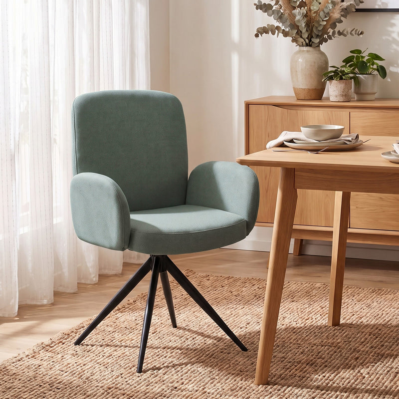 Light green swivel accent chair pulled up to a wooden dining table