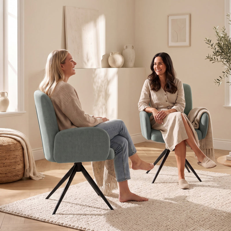 Two women chatting face to face in light green swivel accent chairs