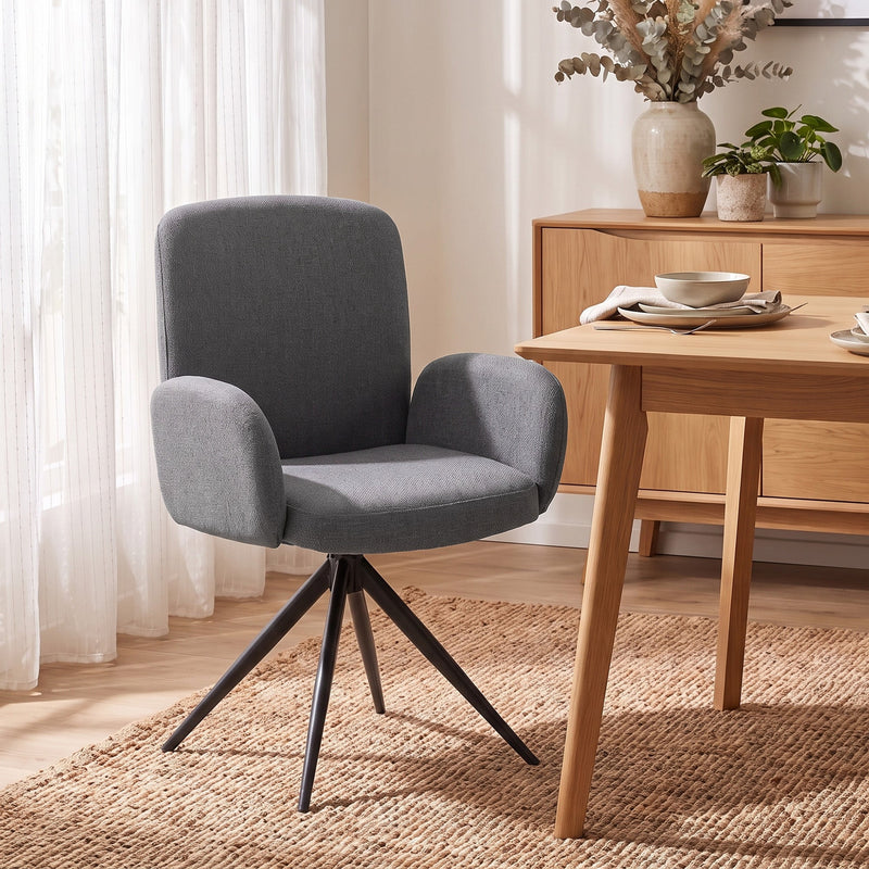 Grey swivel accent chair pulled up to a wooden dining table