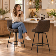 Woman seated on one bar stool with a second stool beside her at a kitchen counter