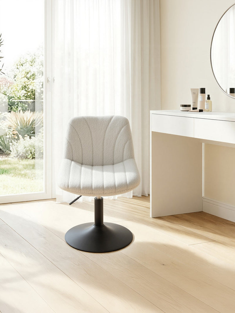 The white dressing table chair beside a white vanity unit and round mirror in a bright bedroom