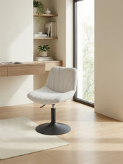 The dressing table chair at a wooden desk in a home office corner with a rug and window