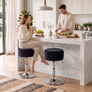 Two black swivel kitchen stools at a white marble island with a couple having breakfast