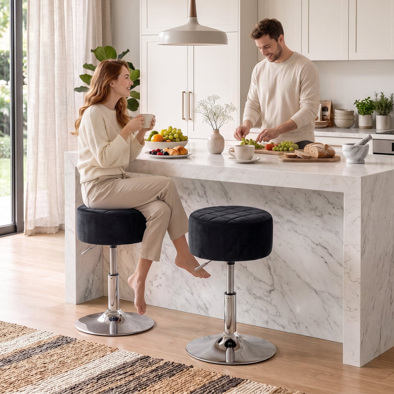 Two black swivel kitchen stools at a white marble island with a couple having breakfast