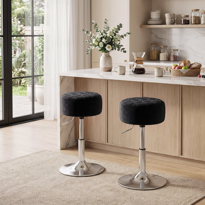 Two black swivel stools beside a wood and marble kitchen island with garden doors behind