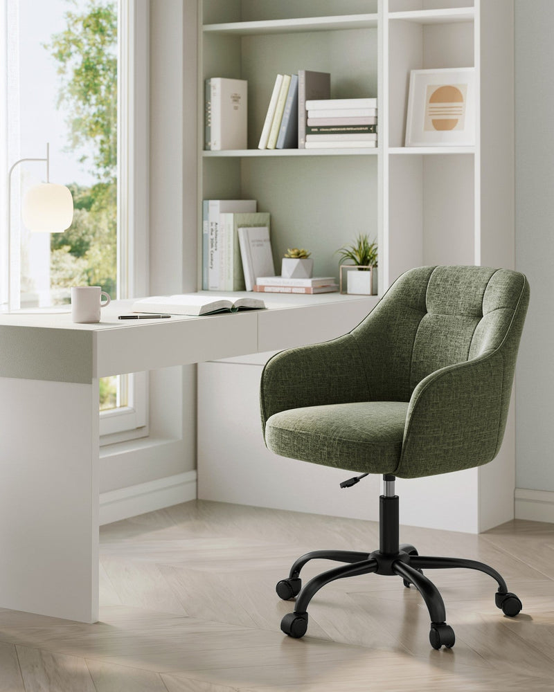 Green swivel chair in a study corner with white shelving and a desk lamp