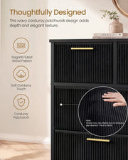 Close-up of fluted black corduroy drawer fronts with a gold handle and a hand on the fabric
