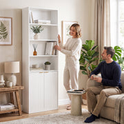 Couple in a living room with the woman reaching for a book on an open shelf