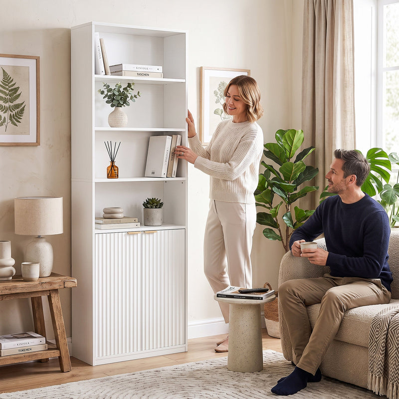 Couple in a living room with the woman reaching for a book on an open shelf