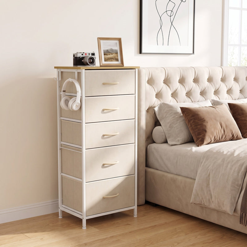 Fabric chest of drawers with headphones on the side hook beside a bed, shown in beige