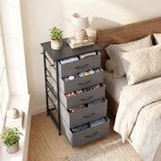 Chest of drawers by a window next to a bed with drawers pulled open, shown in grey