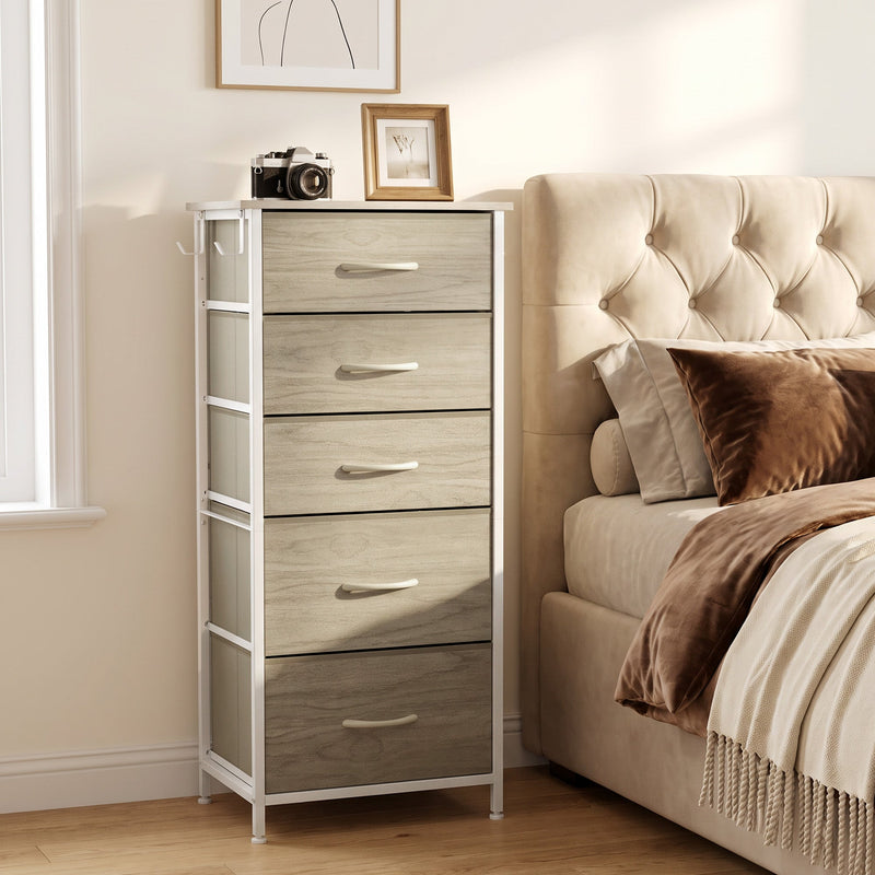Chest of drawers by an upholstered bed with a photo frame and camera on top, shown in oak