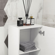 Open cupboard door showing a shelf with folded grey towels and toiletries on top