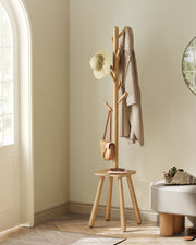 Wooden coat rack stand in a hallway with a coat, sun hat and bag hanging on the hooks