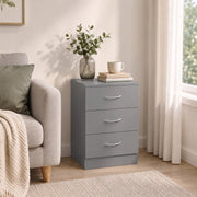 Grey bedside table beside an armchair with a vase and cup on top