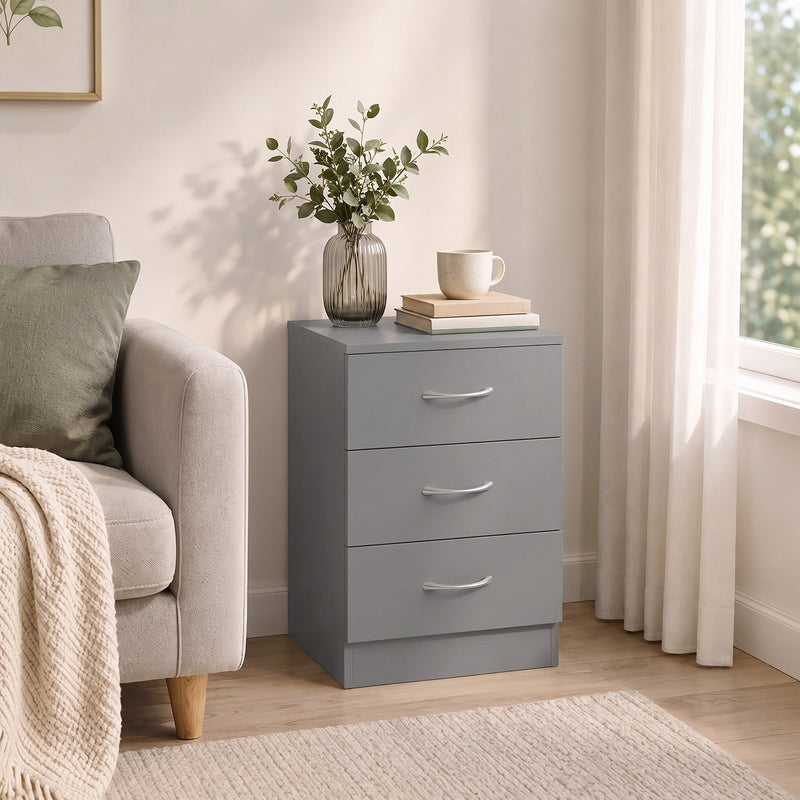 Grey bedside table beside an armchair with a vase and cup on top