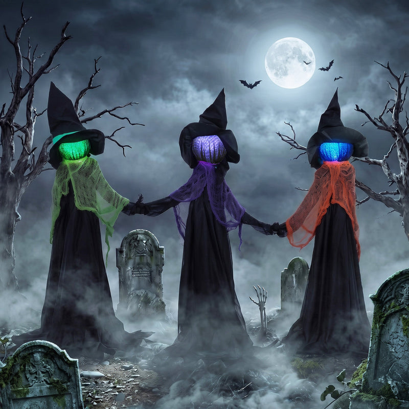 Three witches holding hands display staged in a foggy graveyard under a full moon
