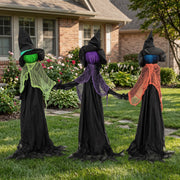 Three witches holding hands staged on a front lawn beside a house