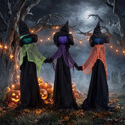Three witches holding hands display among pumpkins and string lights at night
