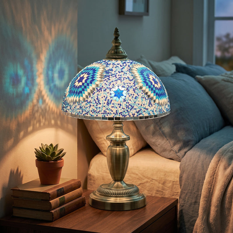 Lit table lamp on a bedside table casting a starburst pattern on the wall at dusk