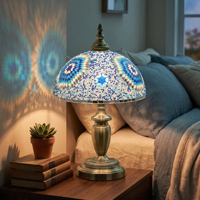Lit table lamp on a bedside table casting a starburst pattern on the wall at dusk