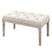 Cream tufted bench with wooden legs shown from a three-quarter angle on a white background