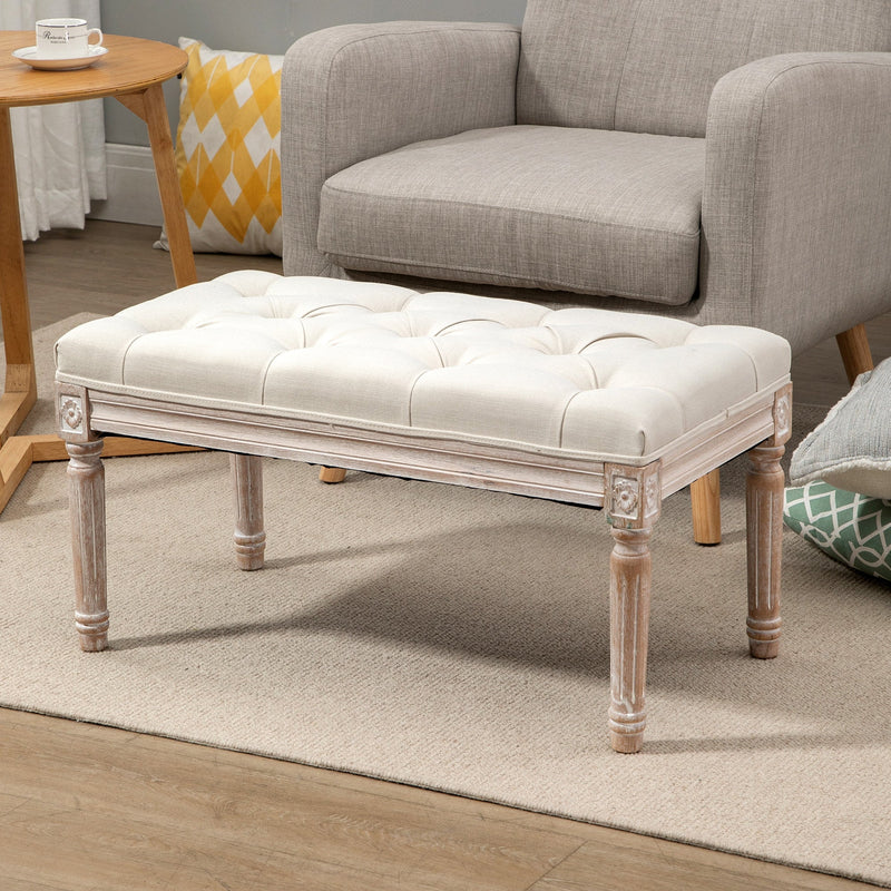Cream tufted bench in a living room in front of a grey armchair