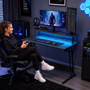 Woman playing with a controller at the two tier desk in a blue lit bedroom