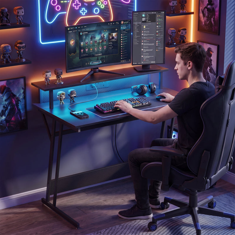 Young man gaming at the desk in a room with neon lighting and shelves of figures
