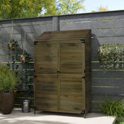 Green wooden shed standing closed against a dark garden fence with climbing plants