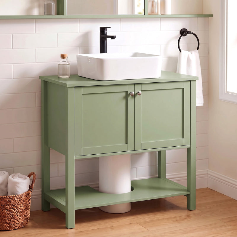 Green under sink cabinet below a vessel sink in a tiled bathroom with a round mirror