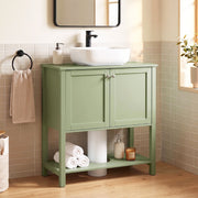 Green under sink cabinet in a bathroom with a vessel sink, black tap and towel rail