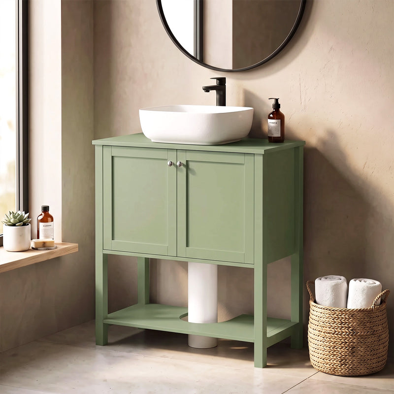 Green under sink cabinet beside a window with a vessel sink and towels on the lower shelf