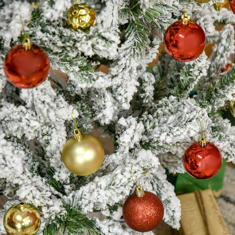 Close-up of flocked branches decorated with red and gold baubles