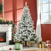 Snow flocked Christmas tree in a red living room beside a fireplace and wrapped presents