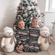 Two children sitting in front of a decorated flocked tree with snowman toys