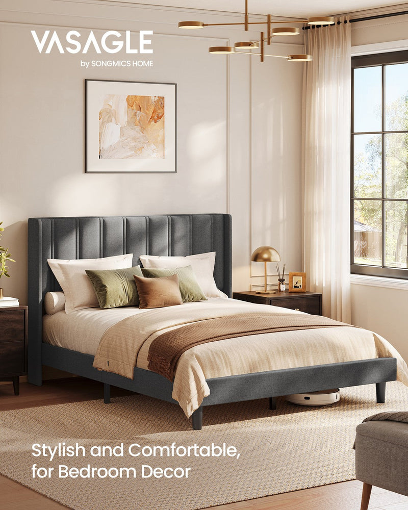 Vasagle slate grey wingback bed dressed with cushions beside a bedside lamp