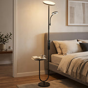 Floor lamp lit beside a bed with the side table holding a book and mug