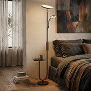 Floor lamp lit in a bedroom corner with the side table holding a mug and glasses