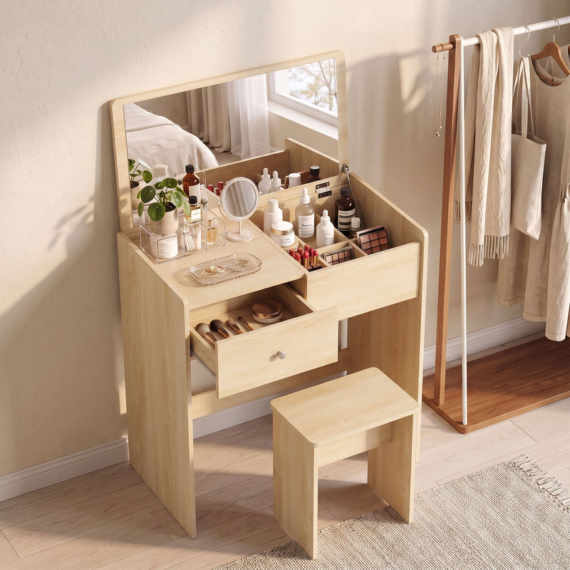 Oak vanity desk with makeup on top, drawer open and stool in a bedroom beside a clothes rail