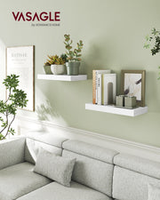 White floating wall shelves mounted above a grey sofa in a living room