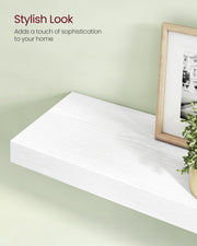 Close-up of the white floating shelf styled with a picture frame and greenery
