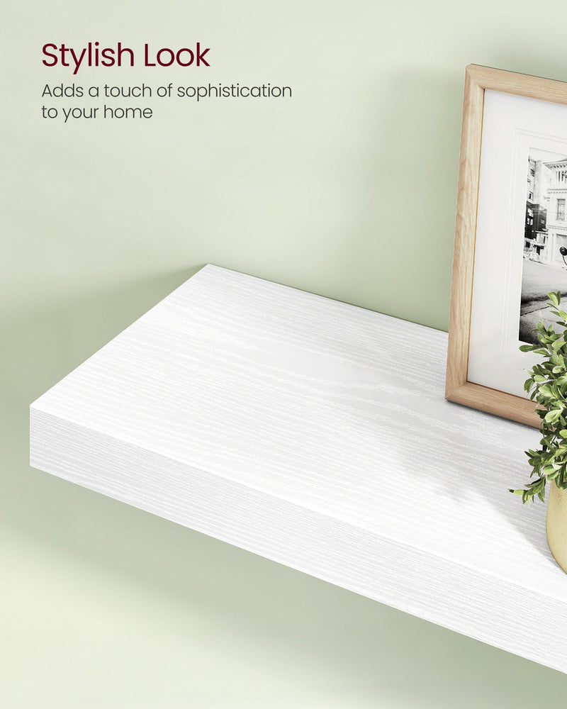 Close-up of the white floating shelf styled with a picture frame and greenery